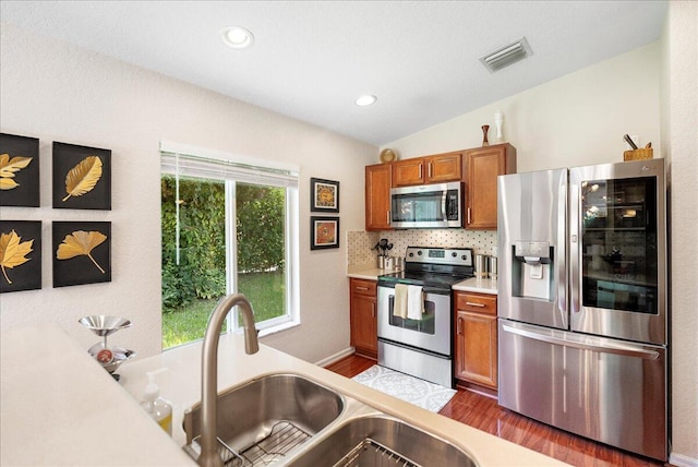 kitchen with lofted ceiling, appliances with stainless steel finishes, plenty of natural light, and dark hardwood / wood-style floors