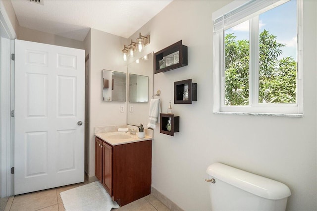 bathroom with tile patterned flooring, a healthy amount of sunlight, toilet, and vanity