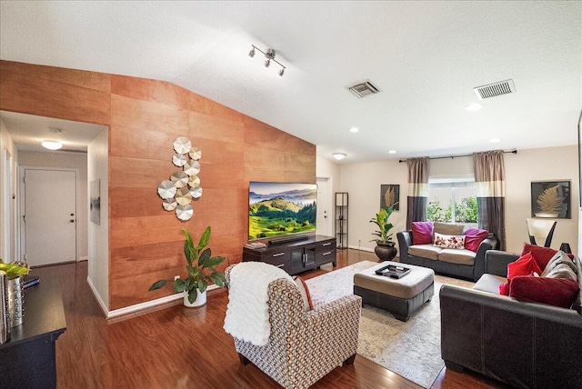 living room with hardwood / wood-style flooring, a textured ceiling, and vaulted ceiling