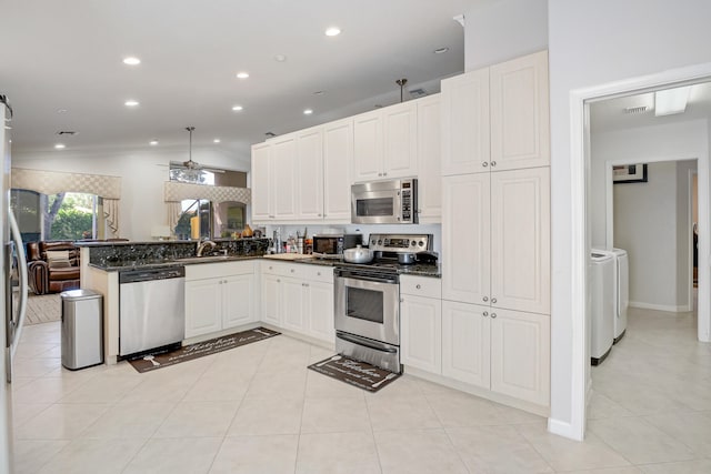 kitchen featuring vaulted ceiling, kitchen peninsula, stainless steel appliances, ceiling fan, and washer and dryer