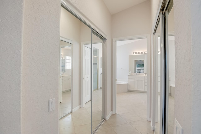 corridor with lofted ceiling and light tile patterned floors