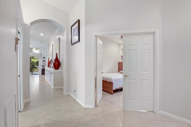 corridor featuring ornamental molding and light tile patterned floors