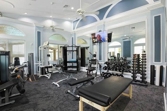 gym featuring ornamental molding, a high ceiling, ceiling fan, and plenty of natural light