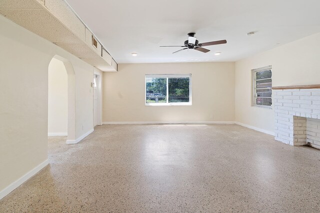 unfurnished living room with ceiling fan and a fireplace