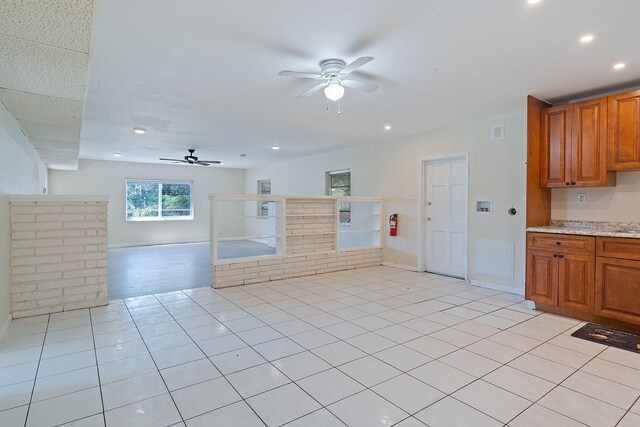 interior space featuring ceiling fan, light tile patterned floors, and light stone countertops