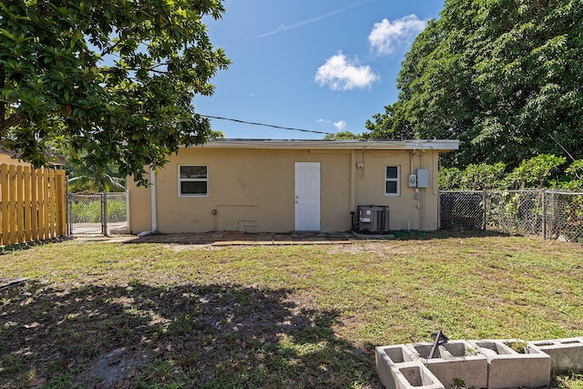 back of property with a yard and central AC unit