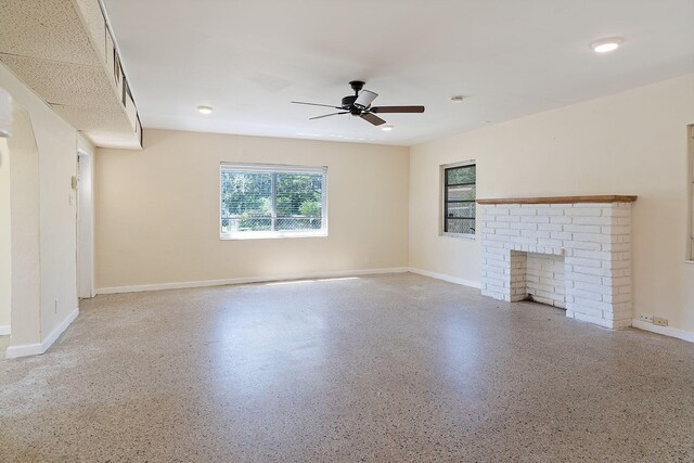 unfurnished living room with ceiling fan and a fireplace