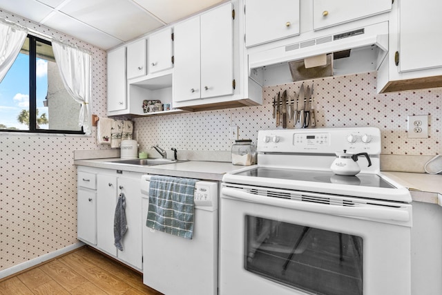 kitchen with white appliances, under cabinet range hood, a sink, light countertops, and light wood-type flooring