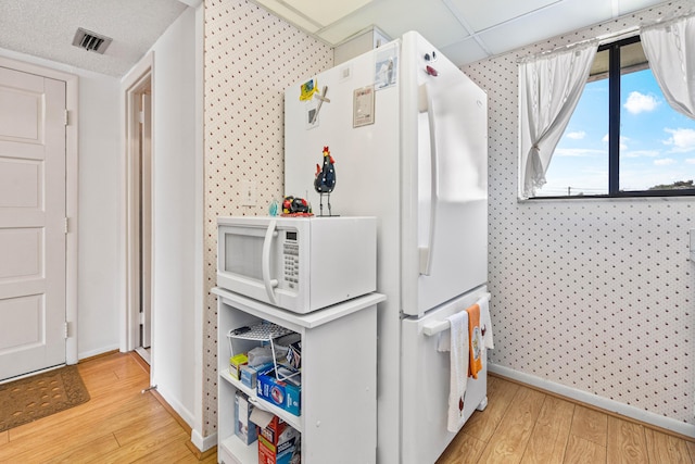 kitchen featuring white microwave, wood finished floors, and baseboards