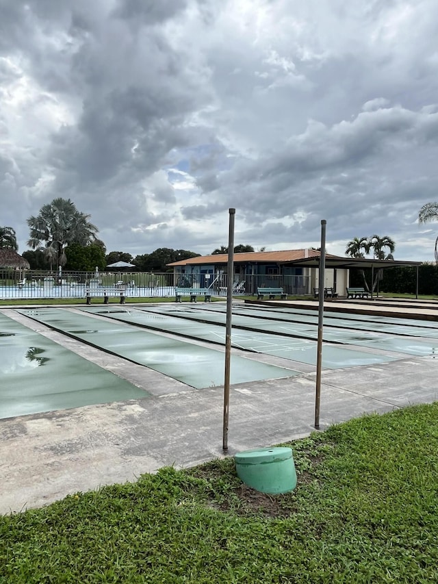 view of property's community featuring fence and shuffleboard