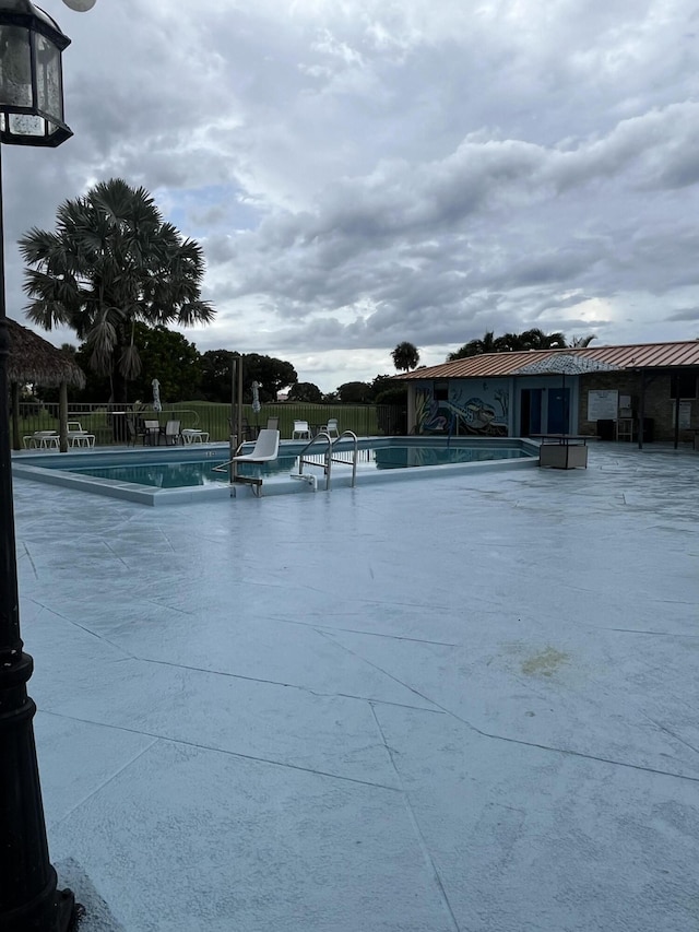 community pool with fence and a patio