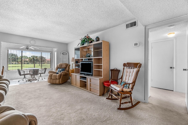 living area with a textured ceiling, light colored carpet, and a ceiling fan