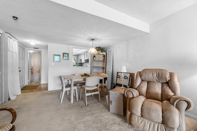 dining room featuring a textured ceiling, light colored carpet, and baseboards