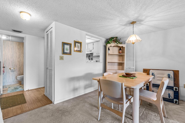 dining area with a textured ceiling and light wood-type flooring