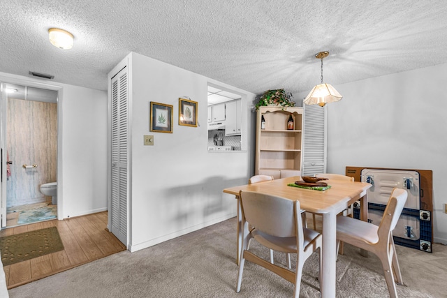 dining space with carpet floors, a textured ceiling, and baseboards