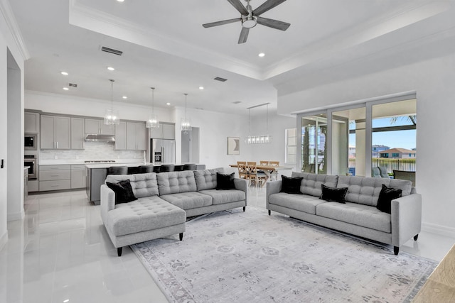 living room with a raised ceiling, crown molding, and ceiling fan