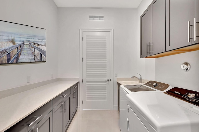 washroom featuring sink, light tile patterned floors, washing machine and dryer, and cabinets