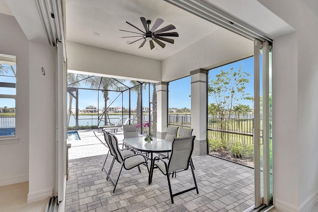 sunroom with ceiling fan and a water view