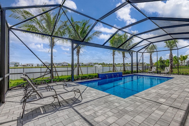 view of swimming pool with pool water feature, glass enclosure, and a patio area