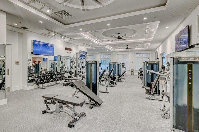 exercise room featuring a tray ceiling, light colored carpet, rail lighting, and ceiling fan