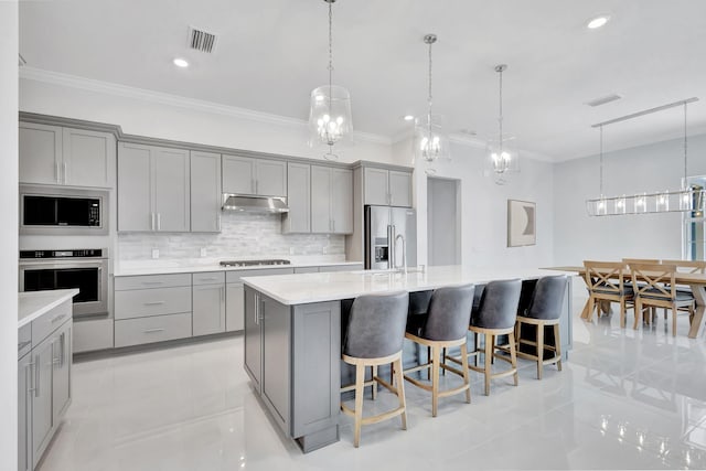 kitchen with stainless steel appliances, a large island, decorative light fixtures, and gray cabinets