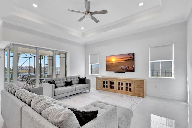 tiled living room featuring crown molding, a tray ceiling, and ceiling fan