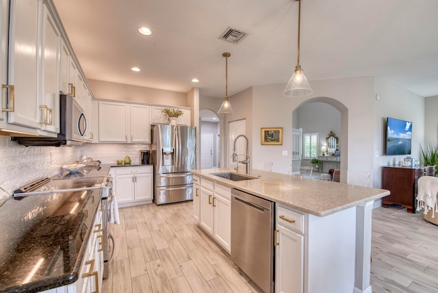 kitchen with sink, stainless steel appliances, an island with sink, pendant lighting, and white cabinets