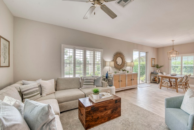 living room with ceiling fan with notable chandelier and light wood-type flooring