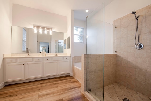 bathroom with wood-type flooring, vanity, and shower with separate bathtub