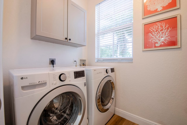 clothes washing area with cabinets, hardwood / wood-style flooring, and washer and clothes dryer