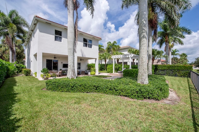 back of property with a pergola, ceiling fan, a lawn, and a patio