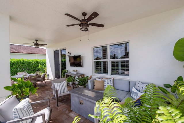 view of patio / terrace with ceiling fan and an outdoor living space with a fire pit