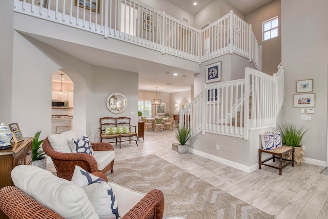 living room with a chandelier, a high ceiling, light hardwood / wood-style flooring, and a healthy amount of sunlight