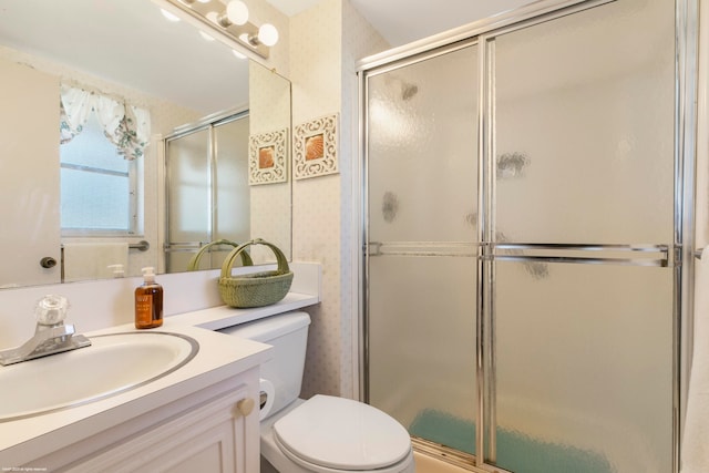 bathroom featuring vanity, toilet, and a shower with shower door