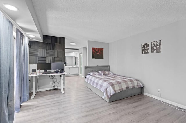 bedroom with a textured ceiling, light hardwood / wood-style flooring, and ensuite bathroom