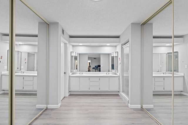 bathroom with vanity, a textured ceiling, wood-type flooring, and a shower with door