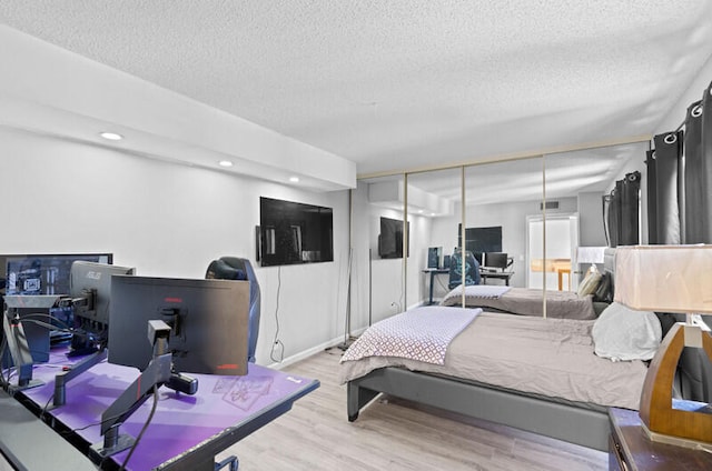 bedroom featuring light wood-type flooring, a closet, and a textured ceiling