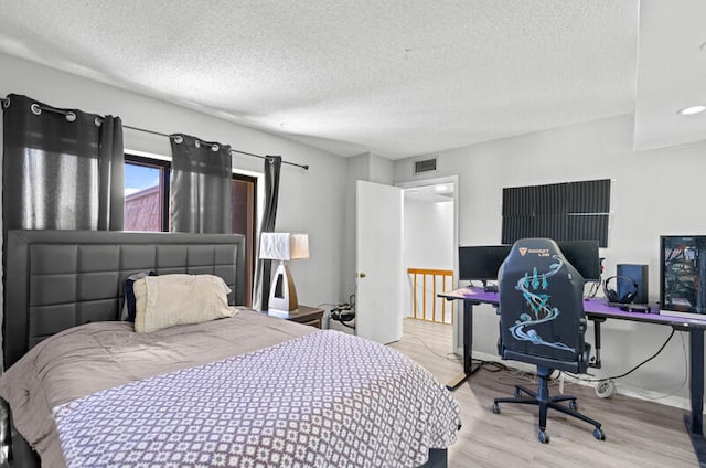 bedroom with a textured ceiling and light hardwood / wood-style flooring