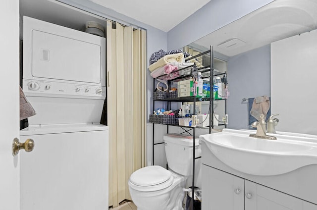 bathroom with toilet, stacked washing maching and dryer, and vanity