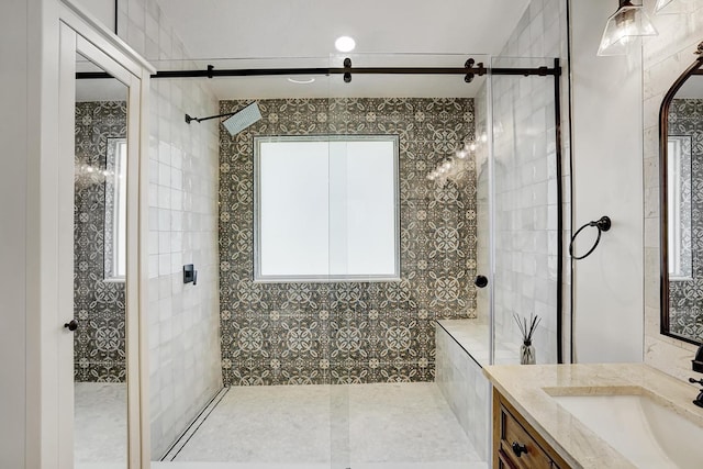 bathroom featuring tiled shower, vanity, and tile walls