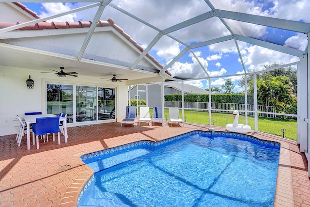 view of pool with glass enclosure, a patio area, a lawn, and ceiling fan