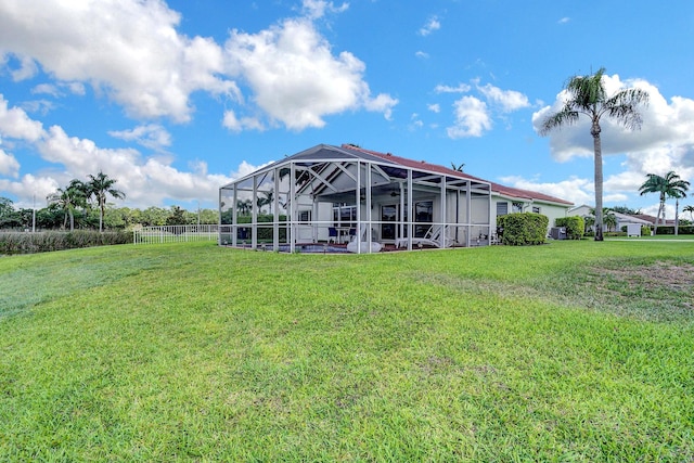 rear view of property featuring glass enclosure and a lawn