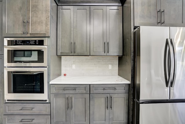 kitchen featuring appliances with stainless steel finishes, light stone counters, and gray cabinetry