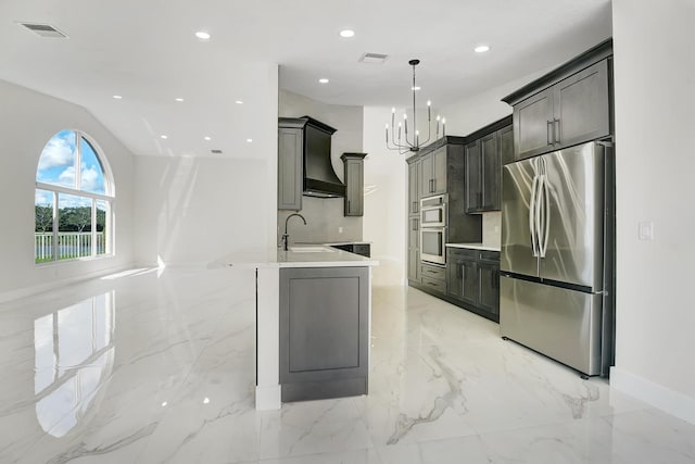 kitchen featuring custom range hood, appliances with stainless steel finishes, hanging light fixtures, sink, and a chandelier