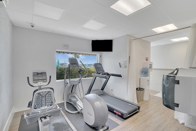 exercise room featuring light wood-type flooring and a paneled ceiling