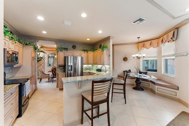 kitchen with an inviting chandelier, appliances with stainless steel finishes, light stone countertops, kitchen peninsula, and a kitchen bar