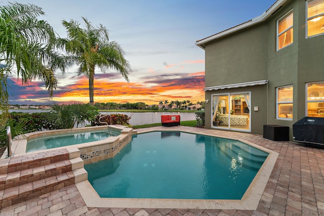 pool at dusk featuring a patio and an in ground hot tub