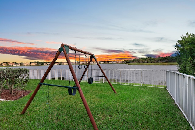 playground at dusk with a water view and a lawn