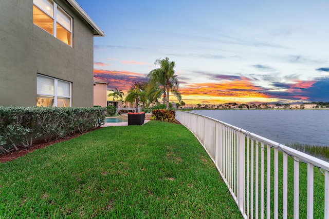 yard at dusk featuring a water view