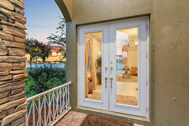 exterior entry at dusk featuring a water view and french doors